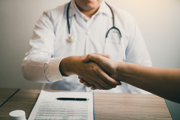 Doctor shaking hands with older patient in a clinic room